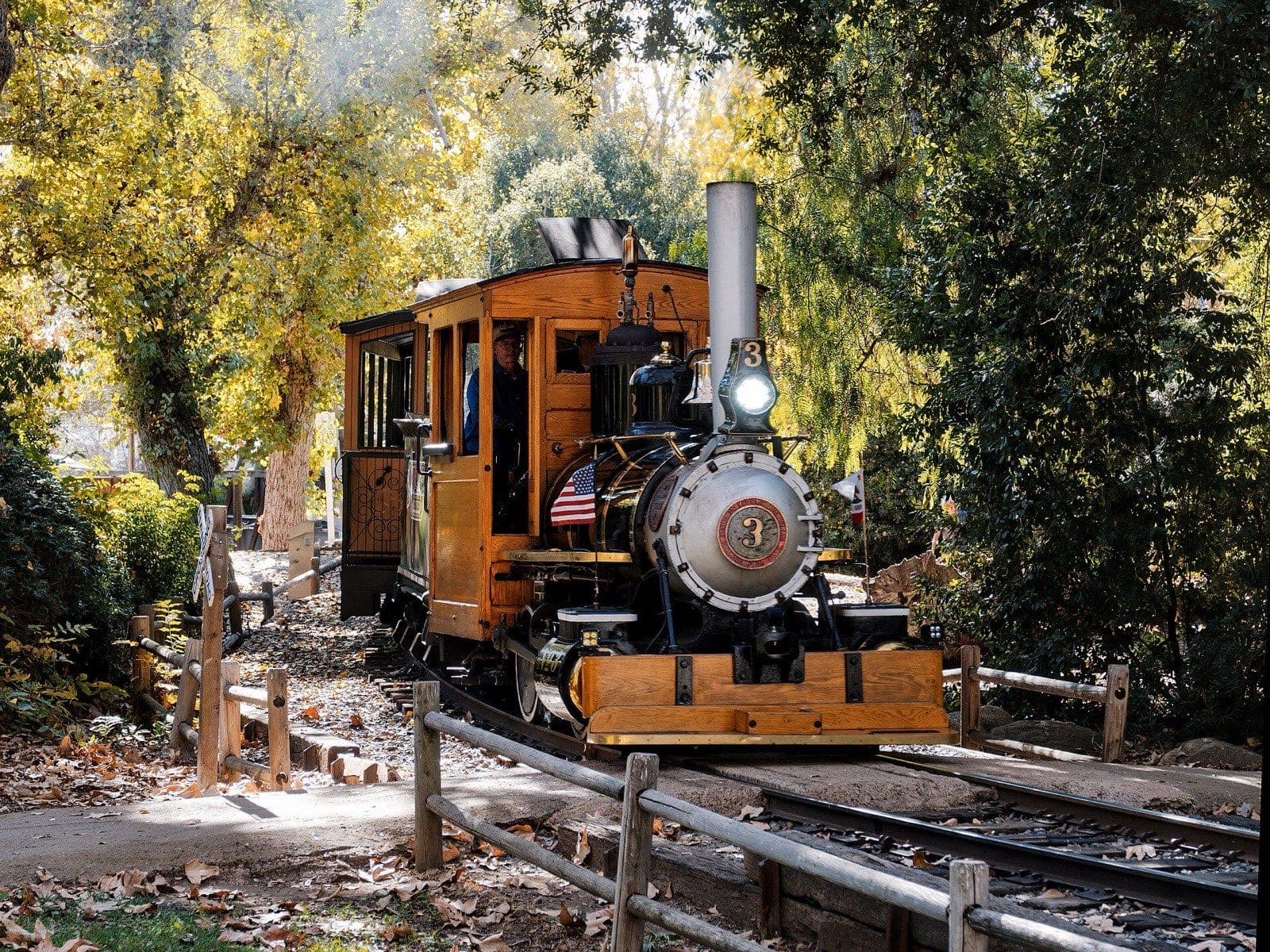 Steam locomotive No. 3 of the Poway-Midland Railroad rounding a bend among autumn trees in Old Poway Park.