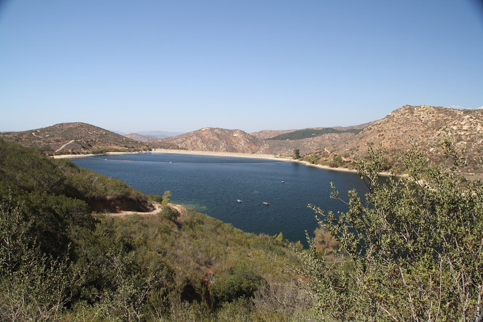 Lake Poway with two small boats, the dam and dry hills, seen from the Mount Woodson Trail.