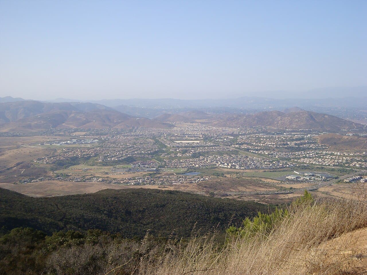 Hazy aerial view from Black Mountain over the 4S Ranch valley, with rows of homes among brown hills.